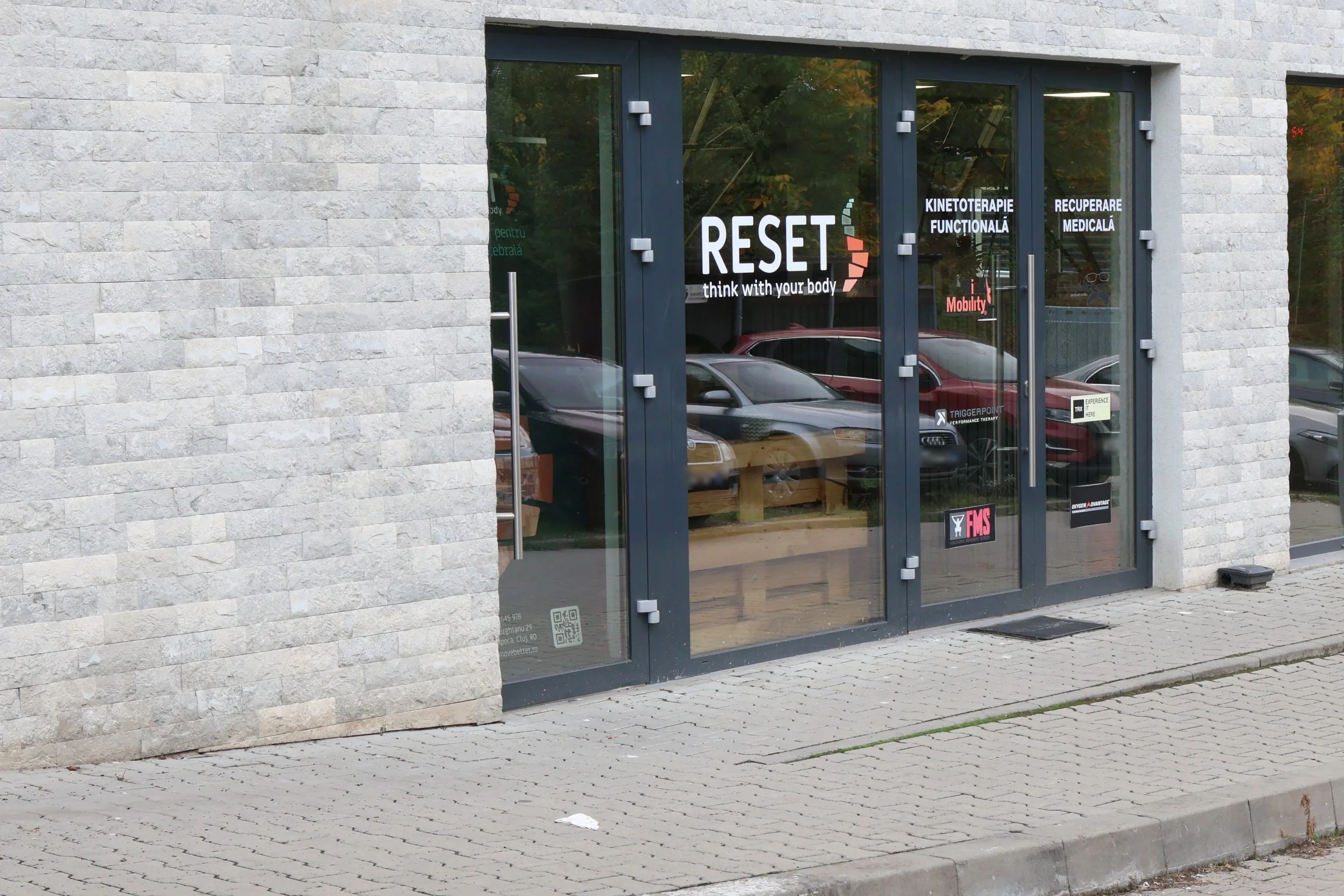 Intrarea centrului RESET de pe Strada Aurel Gurghianu 29, Cluj-Napoca, cu logo-ul și inscripțiile Kinetoterapie funcțională și Recuperare medicală pe vitrină